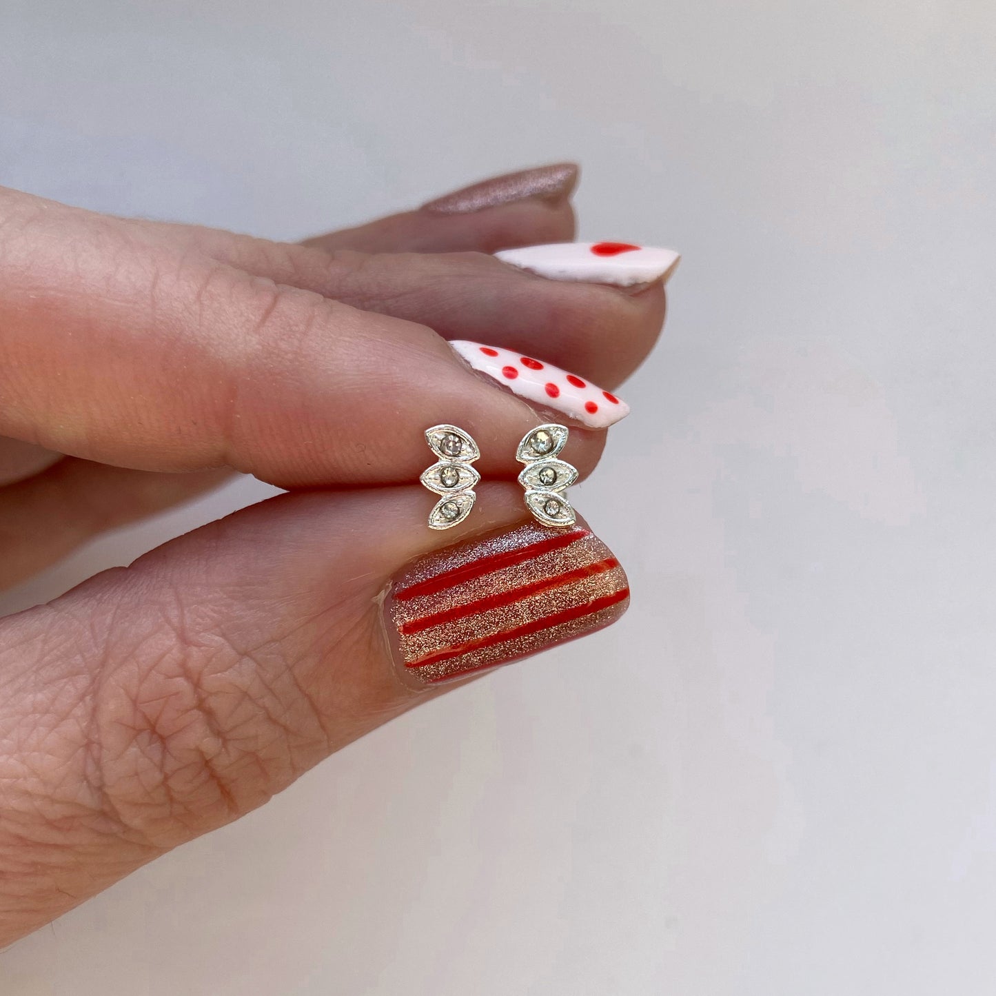 Treble gem set lotus leaf studs. Clear gem encrusted lotus leaf stud earrings. A detailed pair of silver stud earrings bejewelled with clear gemstones set in a pointed ellipse shape, equisitely made in sterling silver. Each stud measures 8mm across.